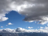 a cloudy sky with mountains in the background