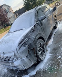 a gray suv is being washed on the side of the street