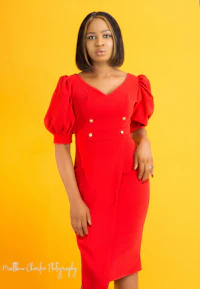 a woman in a red dress posing against a yellow background