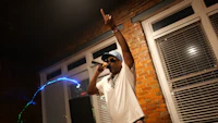 a man is holding a microphone in front of a brick wall