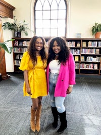 two women standing next to each other in a library
