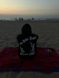 a person sitting on a towel on the beach