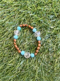 a wooden bracelet with turquoise beads on the grass