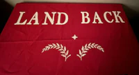 a red blanket with the word land back on it