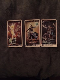three tarot cards sitting on a blanket