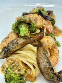 a plate of pasta with shrimp, broccoli and mushrooms