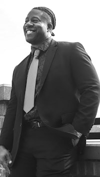 a black and white photo of a smiling man in a suit