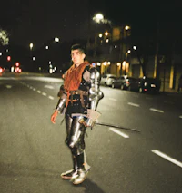 a man in armor standing on a street at night