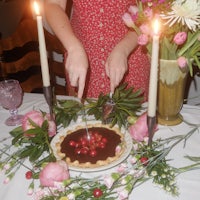 a woman cutting a chocolate cherry pie on a table