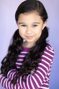 a young girl in a purple striped shirt posing for a photo