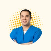 a man in blue scrubs with his arms crossed in front of a yellow background