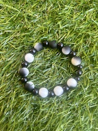 a black and white bracelet laying on grass