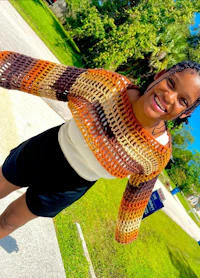a young woman wearing a crocheted sweater and shorts