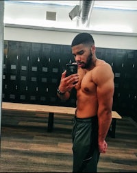 a shirtless man taking a selfie in a locker