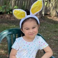 a little girl sitting in a chair with bunny ears
