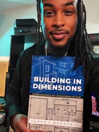 a man holding up a book called building in dimensions