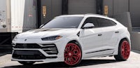 a white lamborghini urus with red rims