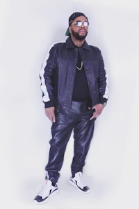 a man wearing a black leather jacket and white sneakers