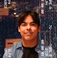 a young man smiling in front of a computer screen