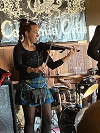 a woman in a scottish kilt playing the violin