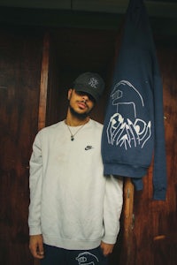 a man wearing a hoodie standing next to a door