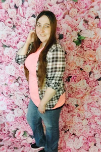 a girl posing in front of a pink flower wall