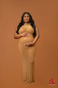 a pregnant woman in a gold dress posing for a photo