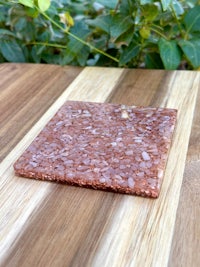 a pink stone coaster on top of a wooden table