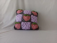 a crocheted strawberry pillow on a bed