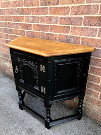 a black and wood sideboard with a brick wall behind it