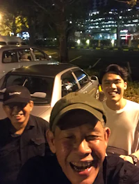 three men standing in front of a car at night
