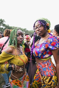two women in colorful outfits posing for a photo at a festival