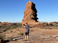 a woman standing in front of a rock formation