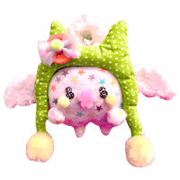 a green and pink owl stuffed animal is sitting on a black background