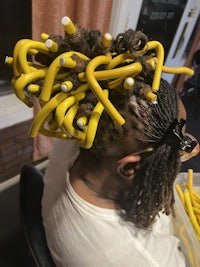 a man sitting in a chair with dreadlocks in his hair