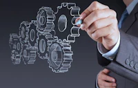 a businessman drawing gears on a blackboard