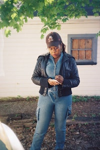 a woman in jeans and a hat looking at her cell phone