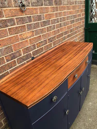 a blue and wood sideboard in front of a brick wall
