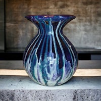 a blue and purple vase sitting on top of a concrete floor