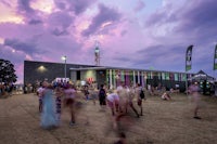 a crowd of people at a festival under a purple sky
