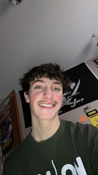 a young man wearing a green t - shirt taking a selfie