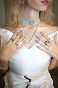 a woman in a white dress with pearls and a choker
