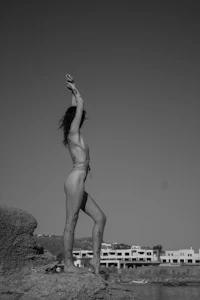 a woman in a bikini standing on a rock