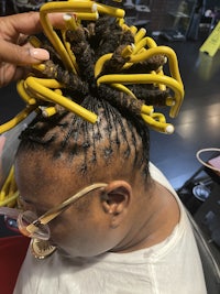 a woman getting her hair braided with yellow dreadlocks