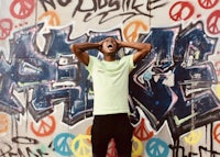 a man standing in front of a wall covered in graffiti