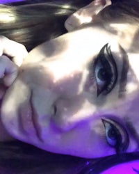 a woman with long black hair and purple eye makeup