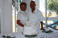 a man and woman standing next to a wedding cake