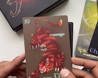a person is holding a tarot card in front of a box