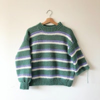 a green and purple striped sweater hanging on a wall