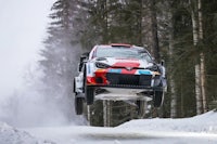 a toyota rally car jumping over a snowy forest